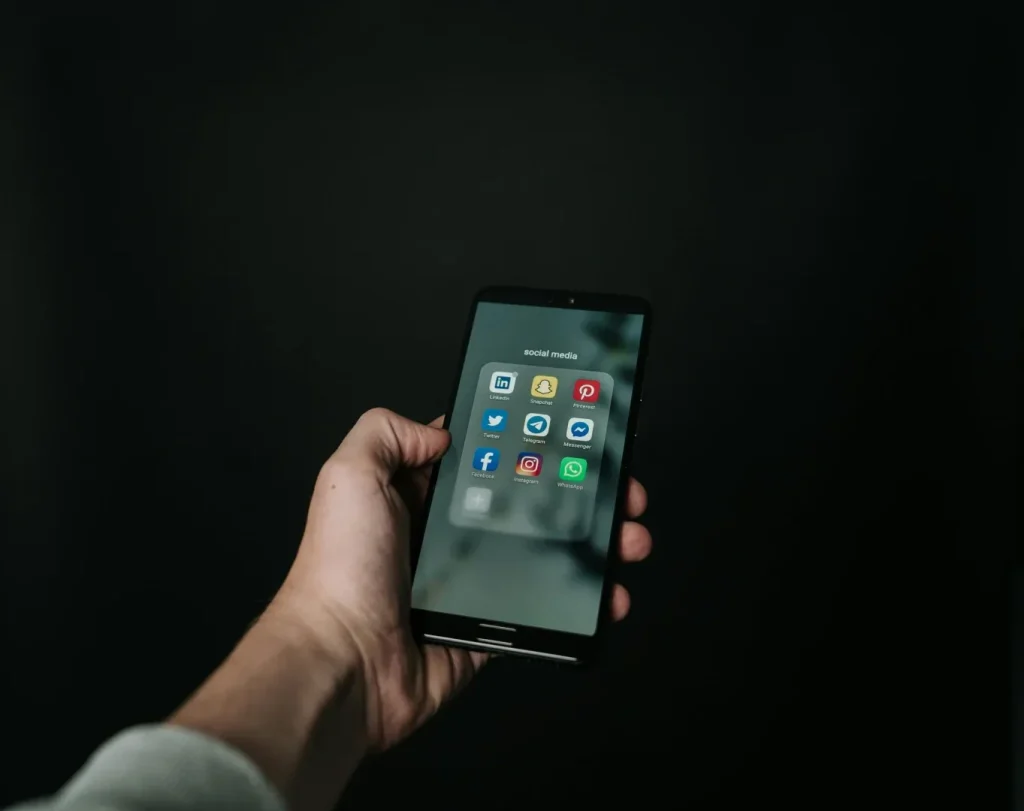 man holding phone with social media apps